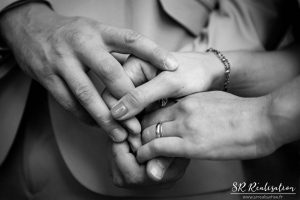 Photo de mariage en gros plan sur les mains des mariés entrelassées, noir et blanc